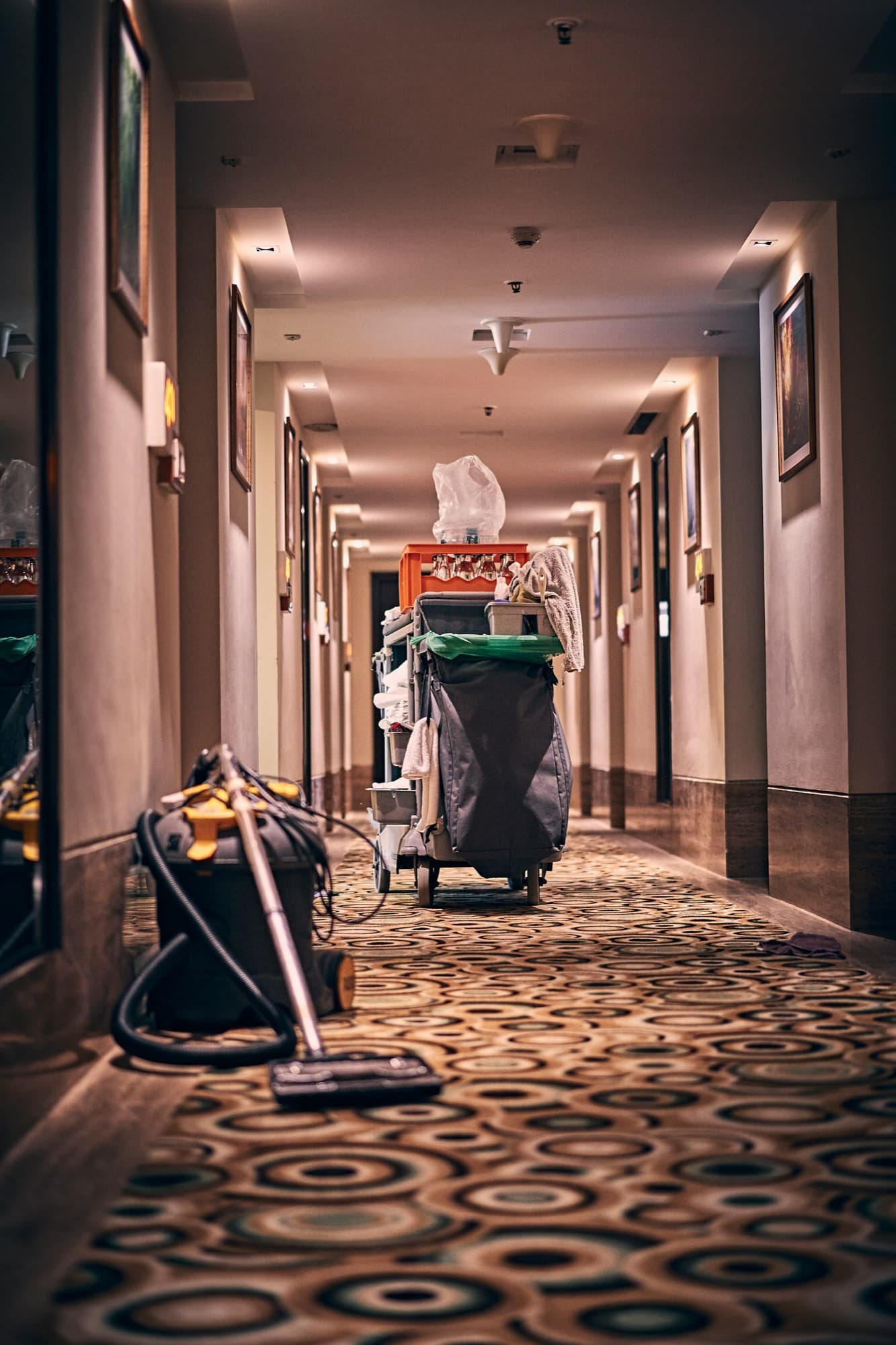 Cleaning trolley and vacuum cleaner ready in a carpeted corridor